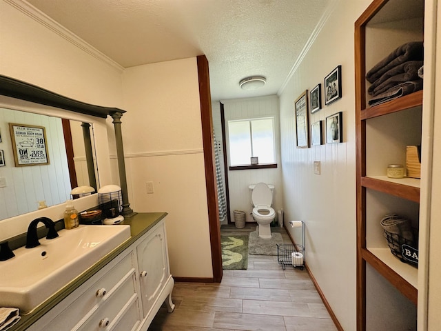 bathroom with vanity, a textured ceiling, toilet, and ornamental molding