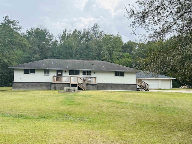 rear view of house featuring a lawn, a wooden deck, an outbuilding, and a garage