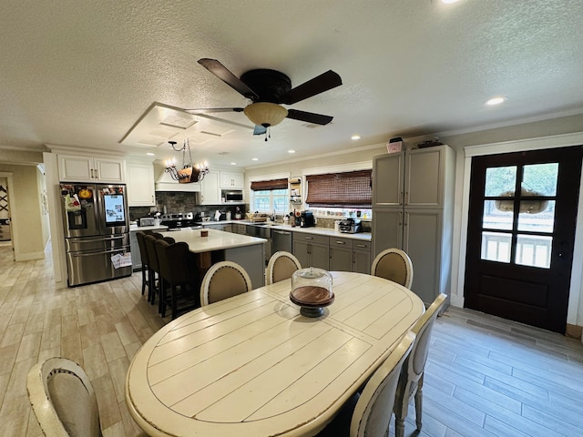 dining space with a textured ceiling, a wealth of natural light, and ceiling fan with notable chandelier