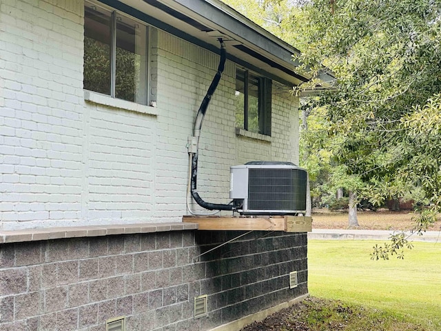 view of side of home featuring cooling unit and a yard