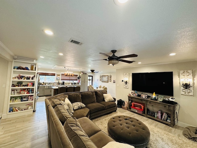 living room with a textured ceiling, light hardwood / wood-style flooring, ceiling fan, and ornamental molding