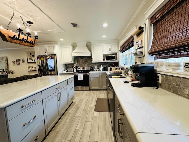 kitchen featuring premium range hood, stainless steel appliances, sink, pendant lighting, and gray cabinets