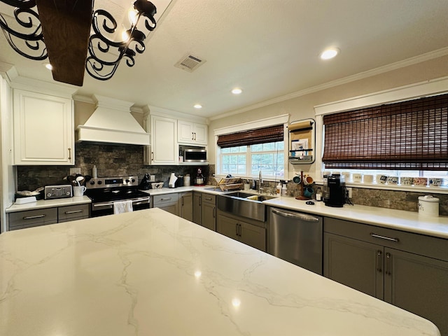 kitchen with gray cabinetry, white cabinetry, appliances with stainless steel finishes, and custom exhaust hood