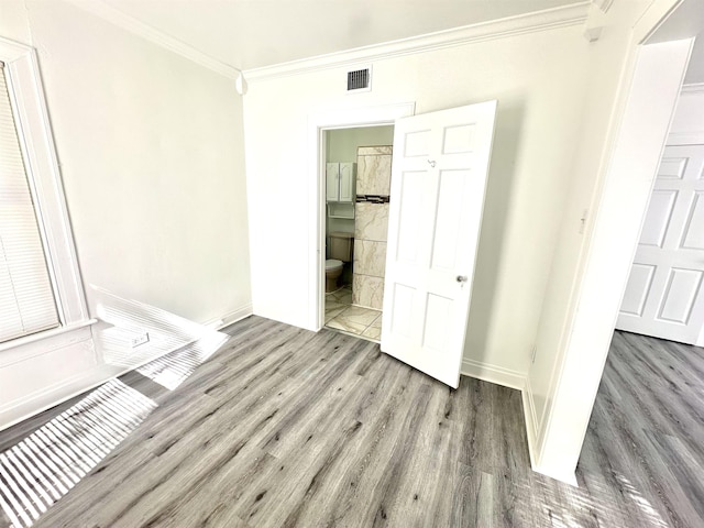 unfurnished bedroom featuring ensuite bath, light hardwood / wood-style flooring, and ornamental molding