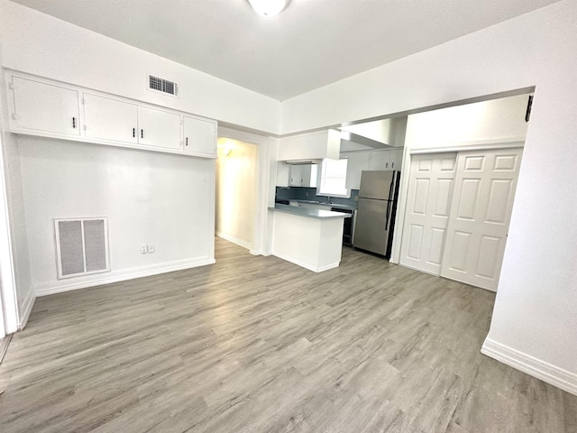 kitchen with stainless steel fridge, white cabinets, and light wood-type flooring