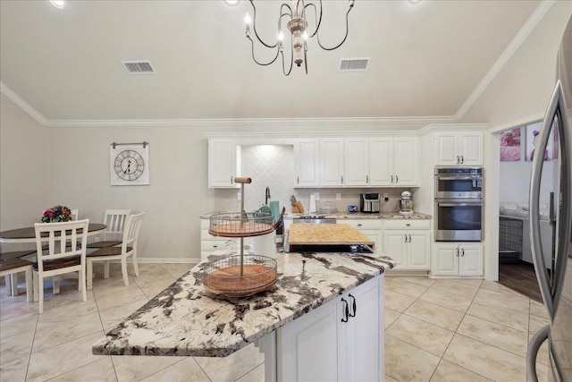 211 Skylark Ave, Bridge City, TX 77611 - kitchen with ornamental molding, a center island, light stone counters, white cabinetry, and a chandelier