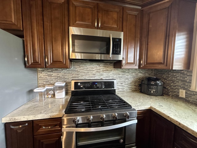 4400 Bethany St, Port Arthur, TX 77642 - kitchen with appliances with stainless steel finishes, backsplash, light stone countertops, and dark brown cabinets