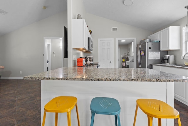 3329 Model Dr, Kountze, TX 77625 - kitchen with stainless steel appliances, a peninsula, white cabinetry, light stone counters, and a breakfast bar area