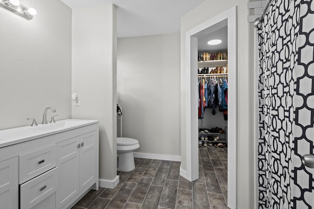 3329 Model Dr, Kountze, TX 77625 - full bath featuring toilet, vanity, a shower with curtain, a spacious closet, and baseboards