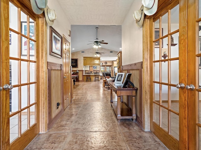 hall with a healthy amount of sunlight, lofted ceiling, a textured ceiling, and french doors