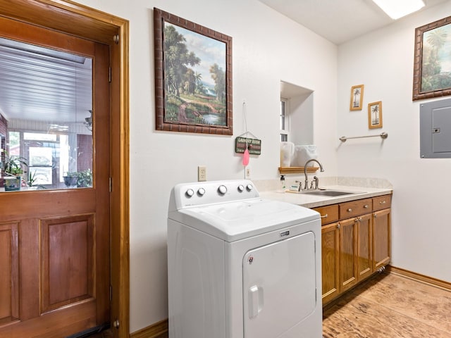 laundry area featuring electric panel, sink, cabinets, and washer / dryer