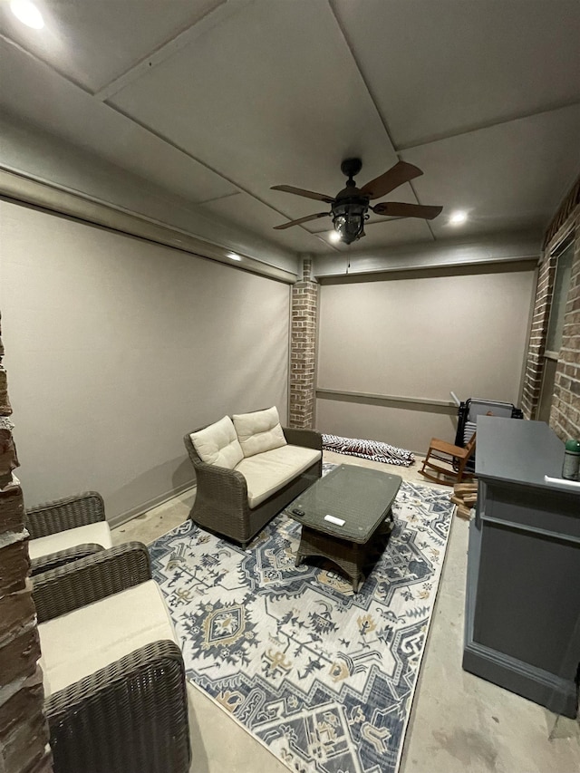 interior space with ceiling fan, brick wall, and concrete flooring