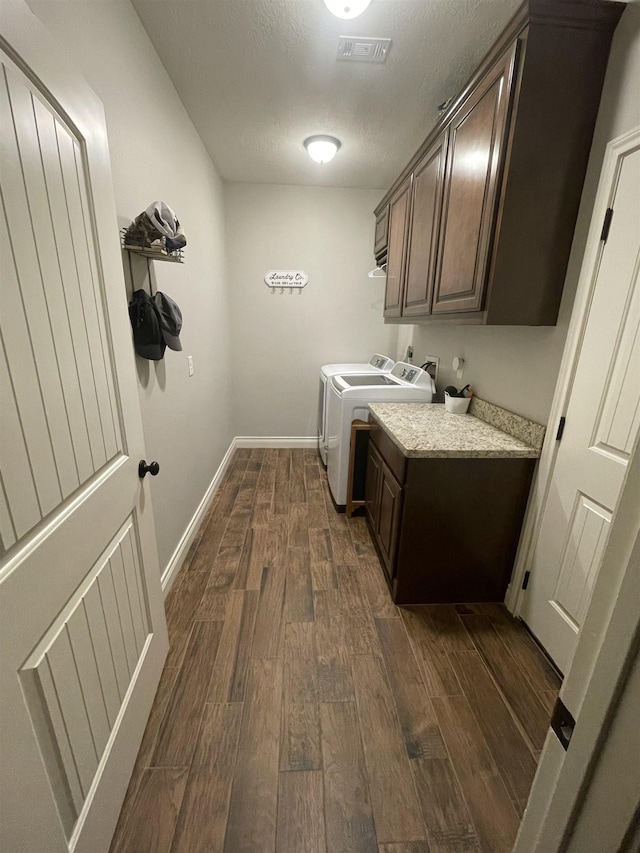 laundry area featuring cabinets, dark hardwood / wood-style flooring, and washer and clothes dryer