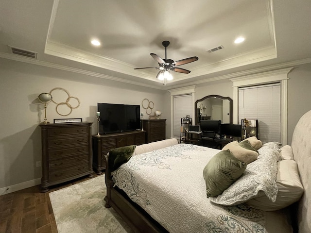 bedroom with hardwood / wood-style flooring, ceiling fan, crown molding, and a raised ceiling