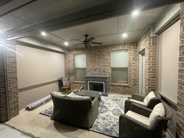 living room with ceiling fan, brick wall, and a fireplace