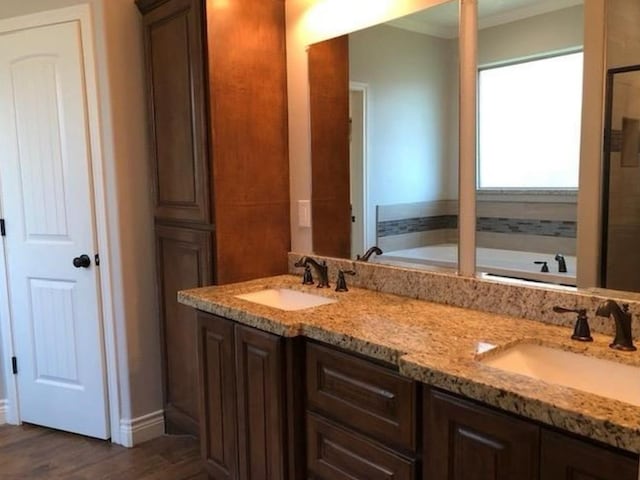 bathroom with wood-type flooring, a bath, vanity, and crown molding