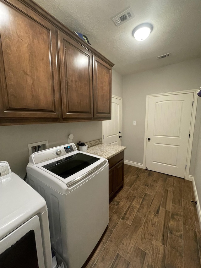 washroom featuring cabinets, washer and dryer, and a textured ceiling