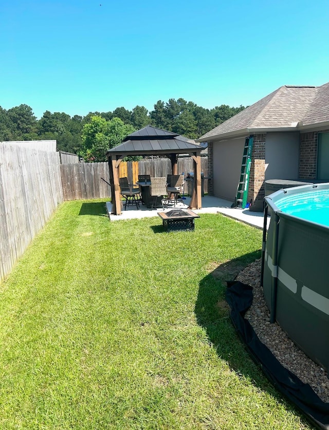 view of yard featuring a fenced in pool, a gazebo, a patio area, and an outdoor fire pit