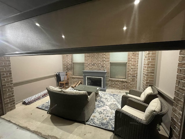 home theater featuring brick wall, concrete floors, and a fireplace