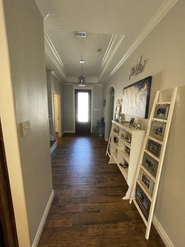 doorway featuring ornamental molding, dark hardwood / wood-style flooring, and a raised ceiling