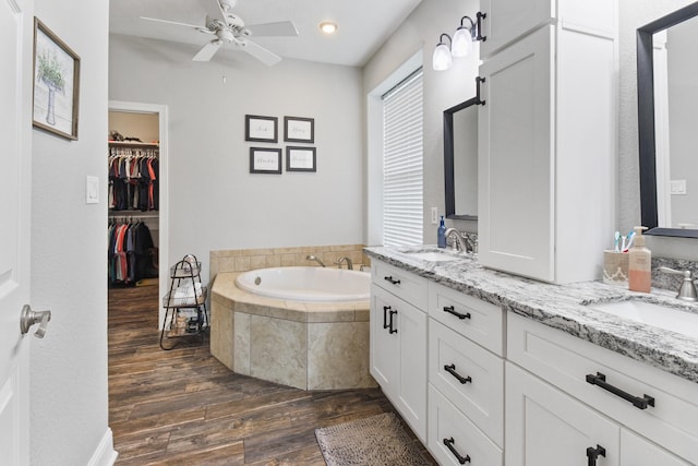 bathroom with tiled bath, vanity, hardwood / wood-style flooring, and ceiling fan