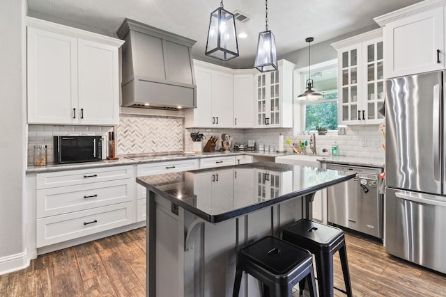 kitchen featuring a kitchen bar, premium range hood, black appliances, white cabinets, and a center island