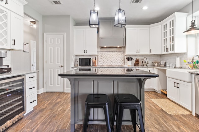 kitchen with a center island, beverage cooler, light stone counters, a breakfast bar area, and white cabinets