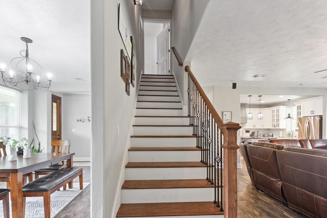 stairs featuring a chandelier, a textured ceiling, and hardwood / wood-style flooring