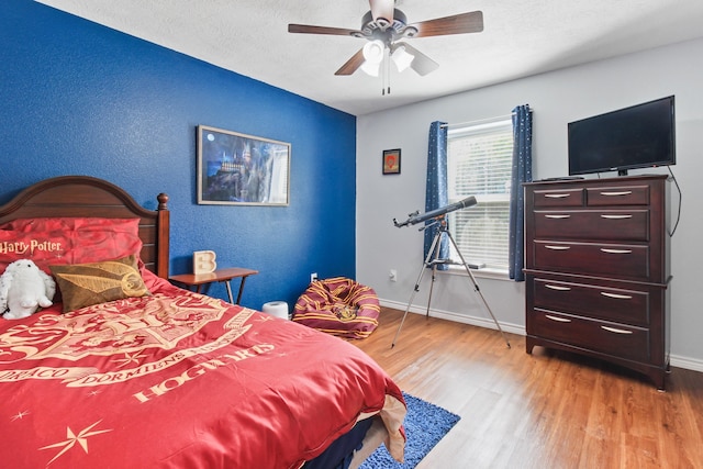 bedroom with a textured ceiling, light hardwood / wood-style flooring, and ceiling fan