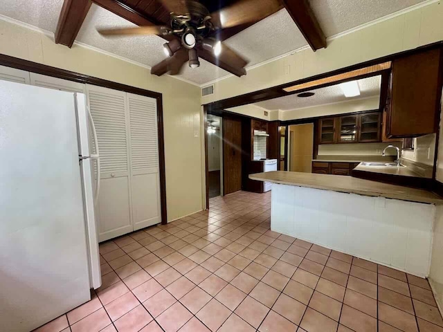 790 Pinchback Rd, Beaumont, TX 77707 - kitchen featuring freestanding refrigerator, beam ceiling, a sink, a textured ceiling, and light tile patterned floors