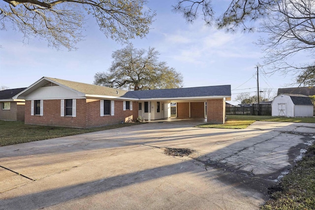 ranch-style house with a storage shed, fence, concrete driveway, and brick siding