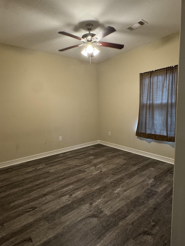 empty room featuring ceiling fan, dark wood-type flooring, and a textured ceiling