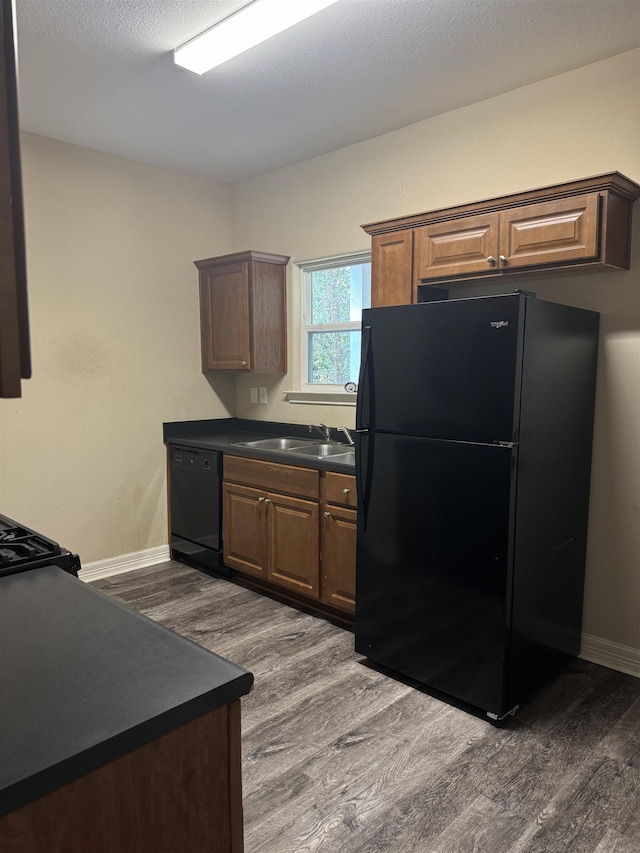 kitchen featuring a textured ceiling, sink, dark hardwood / wood-style floors, and black appliances