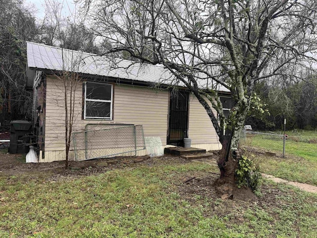 view of home's exterior with fence, metal roof, and a yard