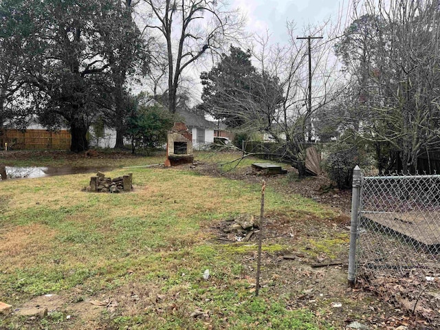 view of yard featuring an outdoor stone fireplace and fence