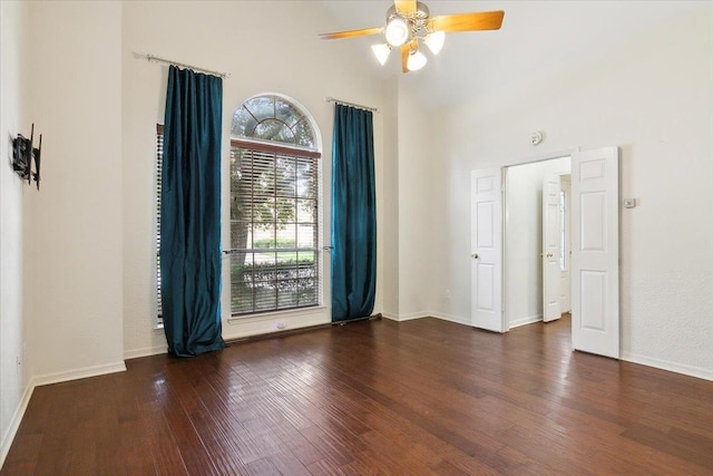 unfurnished room featuring ceiling fan, a towering ceiling, and dark hardwood / wood-style floors