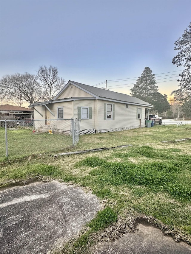 property exterior at dusk with fence and a yard