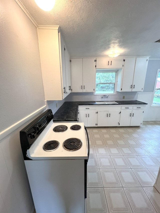 kitchen with white cabinets, a textured ceiling, white range with electric stovetop, and plenty of natural light