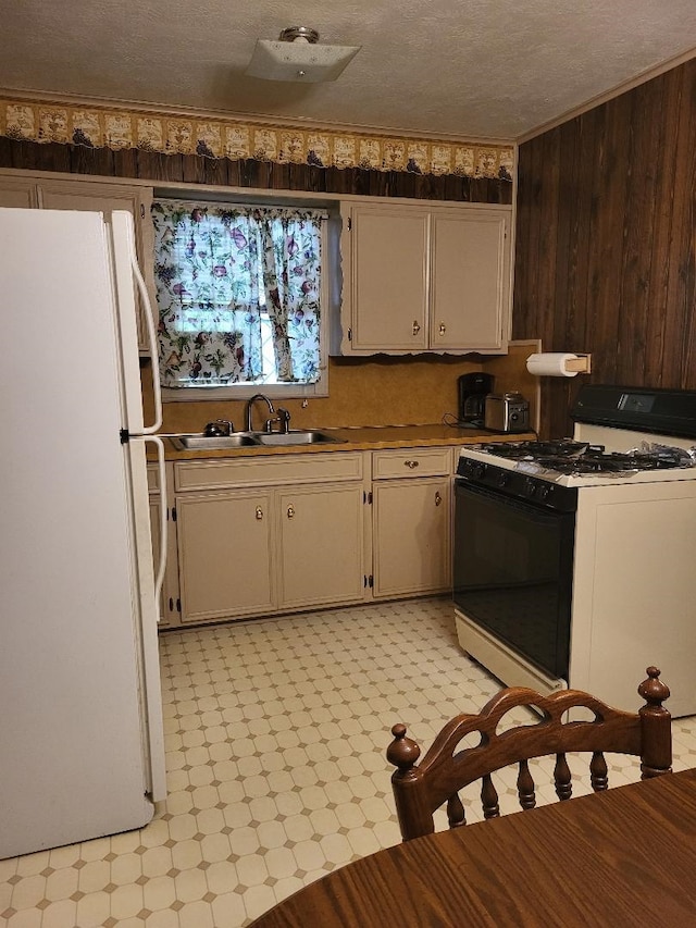 kitchen with sink, wood walls, crown molding, a textured ceiling, and white appliances