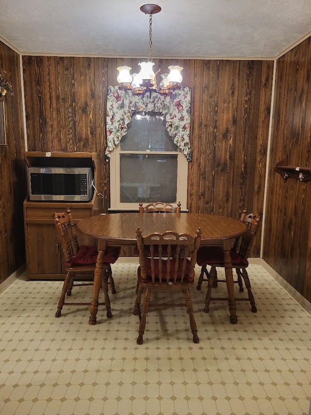 dining room with wood walls, a textured ceiling, and a chandelier