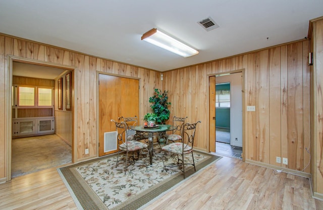 dining area with wooden walls and light hardwood / wood-style floors