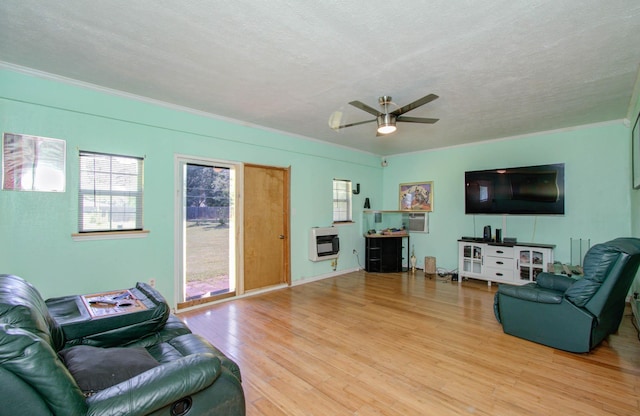 living room featuring ceiling fan, light wood-type flooring, a textured ceiling, and heating unit