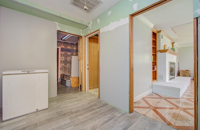 hall with ornamental molding and light hardwood / wood-style flooring