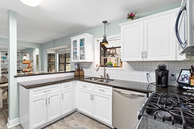 kitchen with stainless steel appliances, white cabinetry, a sink, and backsplash