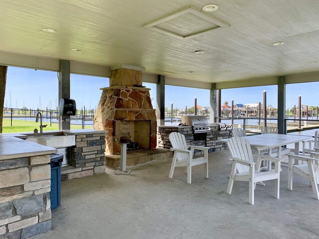 560 Pleasure Island Blvd, Port Arthur, TX 77640 - view of patio / terrace featuring an outdoor stone fireplace, a water view, and a sink