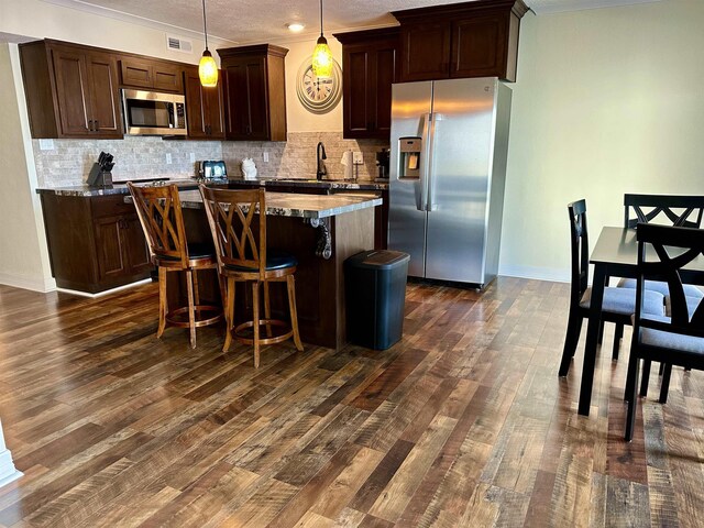 560 Pleasure Island Blvd, Port Arthur, TX 77640 - kitchen featuring appliances with stainless steel finishes, a center island, backsplash, dark brown cabinets, and ornamental molding