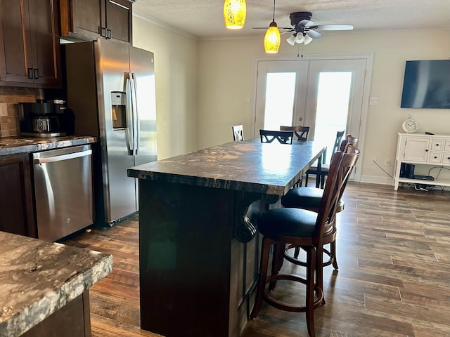 560 Pleasure Island Blvd, Port Arthur, TX 77640 - kitchen featuring stainless steel appliances, dark countertops, a breakfast bar area, a ceiling fan, and crown molding