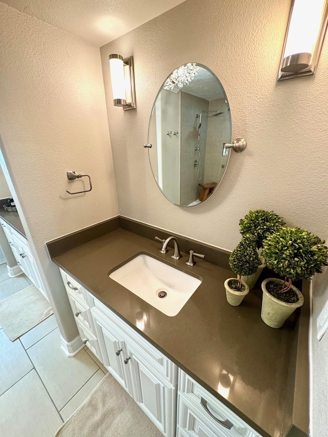 bathroom featuring tile patterned flooring, a shower, and vanity