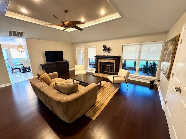 living room featuring dark hardwood / wood-style flooring, crown molding, and a tray ceiling