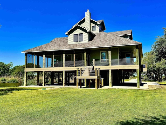 back of property with a lawn, a chimney, and a shingled roof